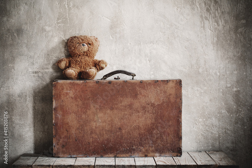 brouwn teddy bear and old suitcase on  grunge background photo