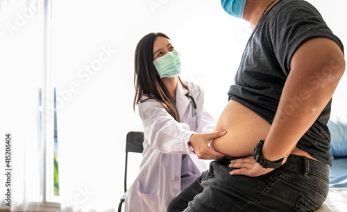 Blurred soft images of Asian woman doctor using a hand to hold the belly fat Of obese man patients, who received treatment for diabetes Caused by obesity, This picture focused on doctor's hand