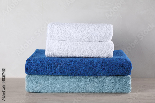 Stacked fresh soft towels on grey wooden table
