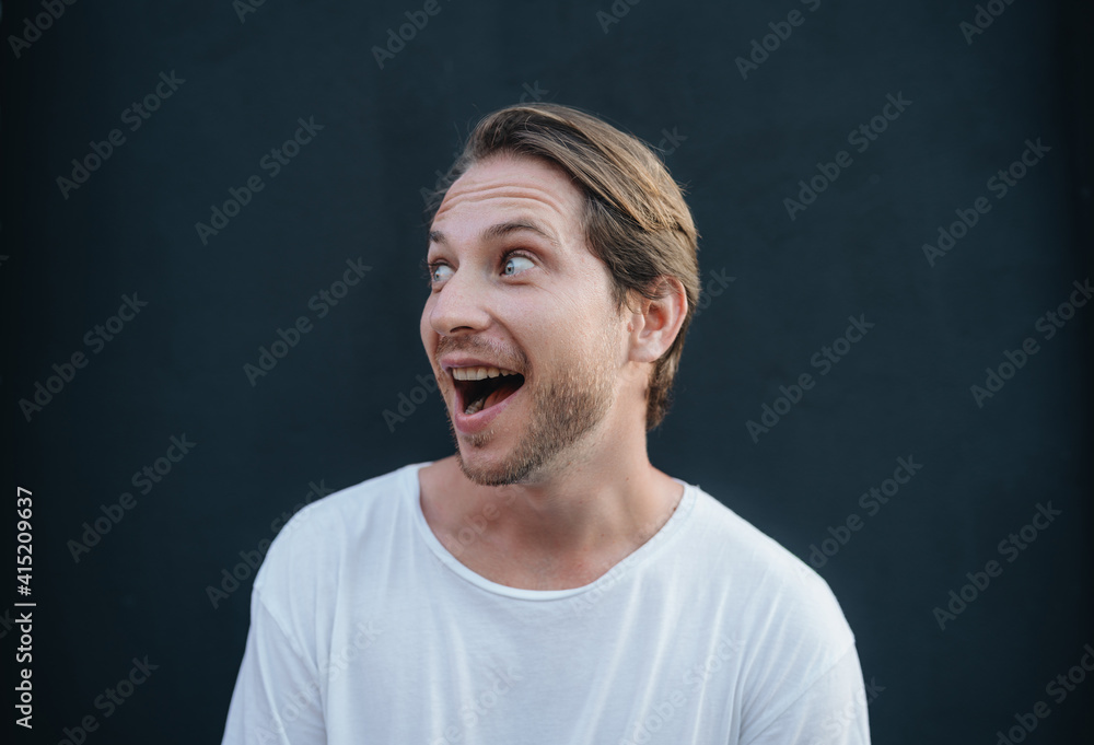 Portrait of european happy man in white t0shirt at dark wall