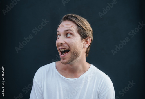 Portrait of european happy man in white t0shirt at dark wall