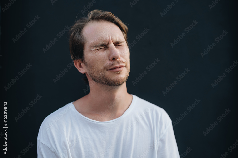 Fototapeta premium A man is saddened with closed-eyes at dark wall