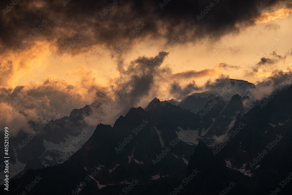 golden sunset over mountain range with dark clouds in the sky