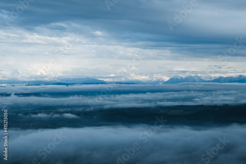 view to the swiss alps with clouds above and fog below