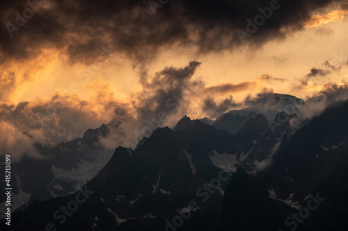 golden sunset over mountain range with dark clouds in the sky