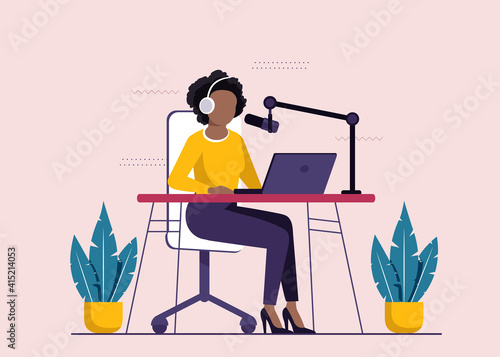 African-american radio host sitting in front of microphone. Young woman in headset working at the radio studio