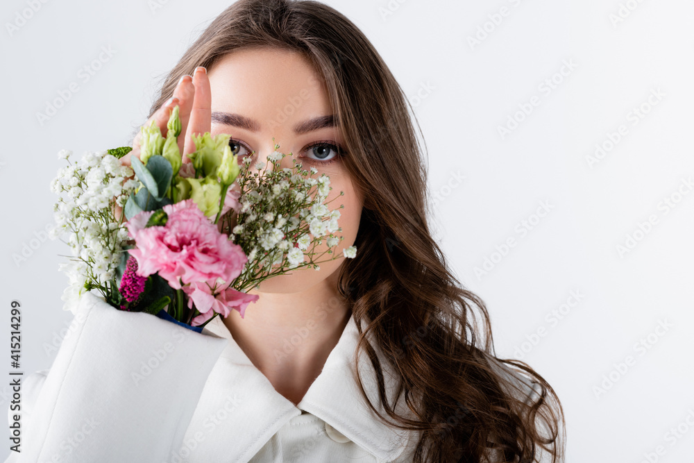Young woman with flowers in sleeve of coat looking at camera isolated on grey Young woman with flowers in sleeve of coat looking at camera isolated on grey