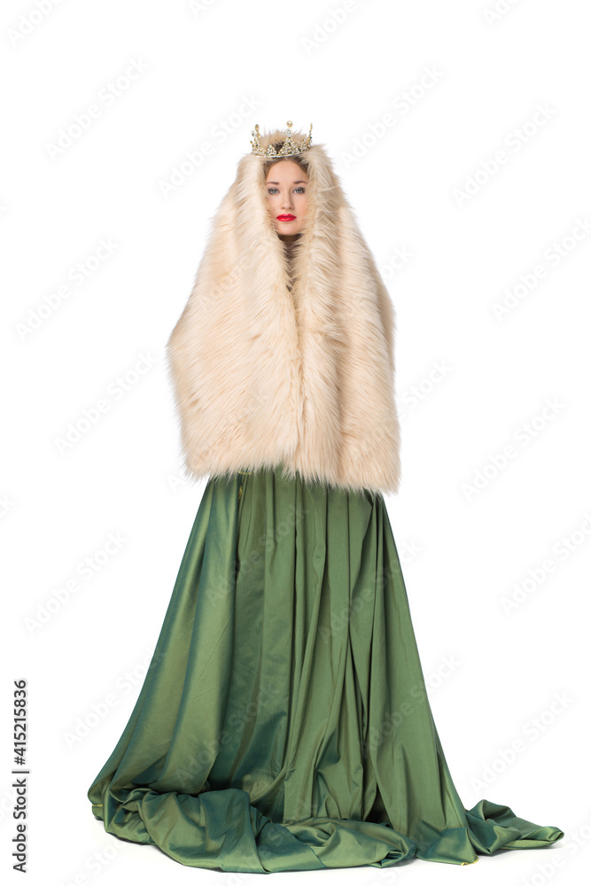 Fototapeta premium Fashion photo of a beautiful elegant young teenager girl with long curly hair in a crown. pretty long green skirt and fur cape isolated on white background. Russian beauty