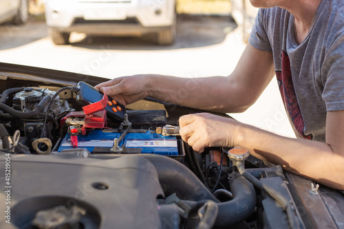 Car battery repair and inspection. The man measures the voltage and capacity of the battery with a tester. Car service