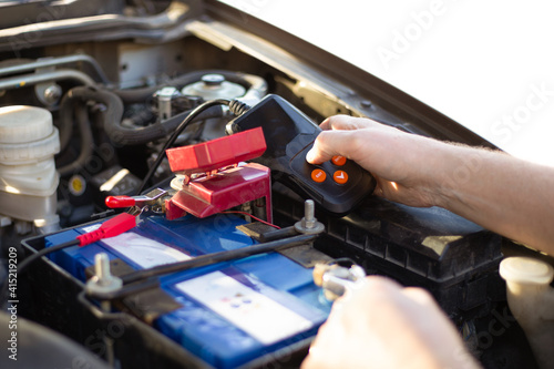 Car battery repair and inspection. The man measures the voltage and capacity of the battery with a tester. Car service