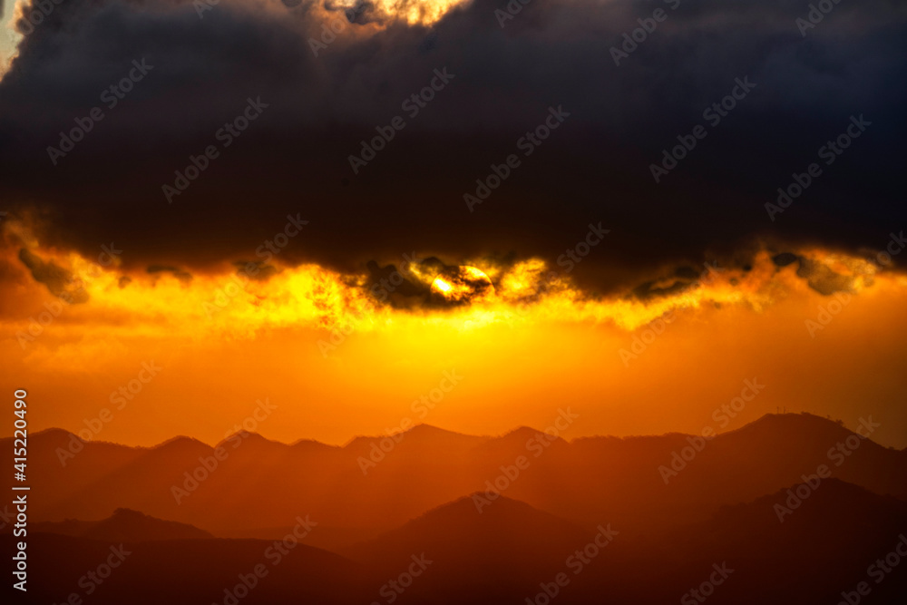 Sunset over mountains light, silhouetted clouds 