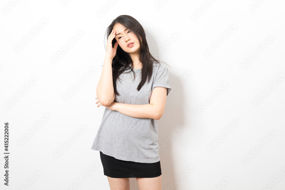Young Asian woman wearing casual t-shirt with hand on head, headache because stress. suffering migraine. Young Asian woman wearing casual t-shirt with hand on head, headache because stress. suffering migraine.