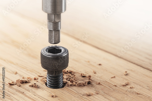hex bolt screw hex bit  in wooden oaks plate. Spanner, bolt, screw and nuts. photo