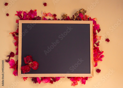 Pizarra sobre fondo de flores con anillos de boda