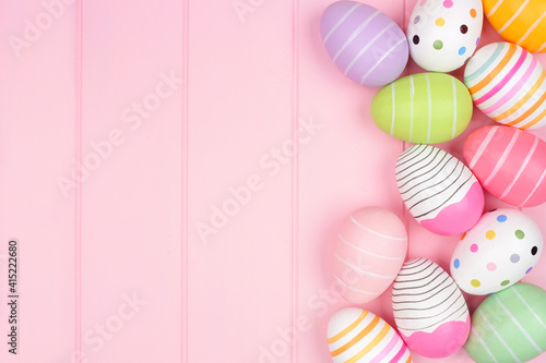 Colorful Easter Egg side border over a soft pink wood background. Top down view with copy space.