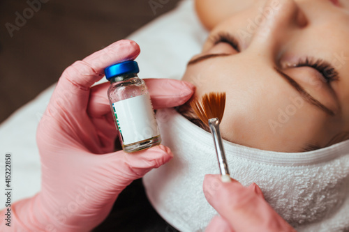 in the hands of a brush and a container with the drug, cosmetology chemical peeling photo