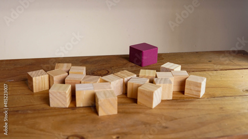 Purple block surrounded by organised wooden block meaning cooperative cooperation. leadership and teamwork concept