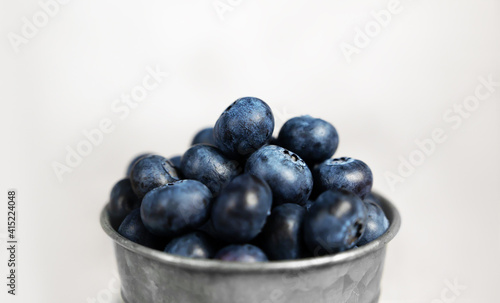 Fresh blueberries in a small metal bucket surrounded with some berries on a checked napkin. Side view. Rustic.