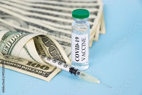 Coronavirus COVID-19 vaccine glass, syringe and money on blue background. Supply and sale of vaccine against virus. Price of COVID19 vaccine pevention, immunization and treatment. photo