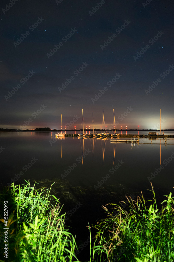 Langzeitbelichtung mit Sternenhimmel und Spiegelung im Wasser am Hafen