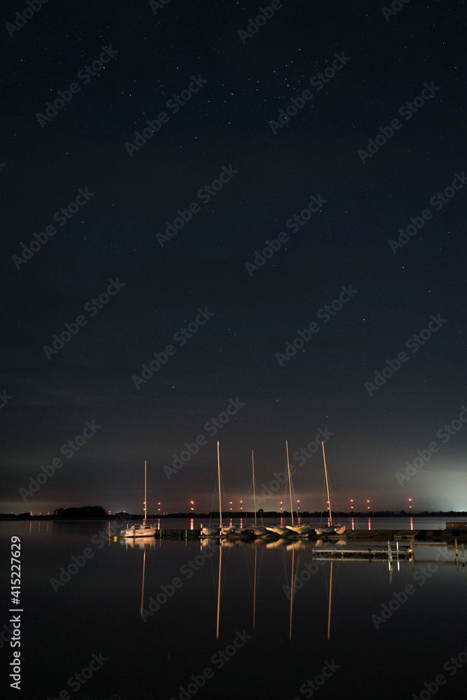 Langzeitbelichtung mit Sternenhimmel und Spiegelung im Wasser am Hafen