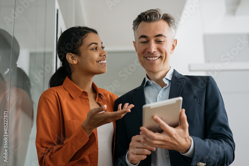 Business people using digital tablet planning start up, sharing ideas at workplace. Smiling successful colleagues working in modern office. Business meeting concept 