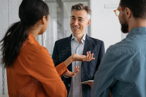 Colleagues meeting, planning start up, talking, cooperation, working in office. Mature confident mentor or business coach teaches people at business seminar, explaining information, sharing ideas 