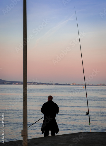 old man mature fishing in the algeciras bay with two fishing rods
