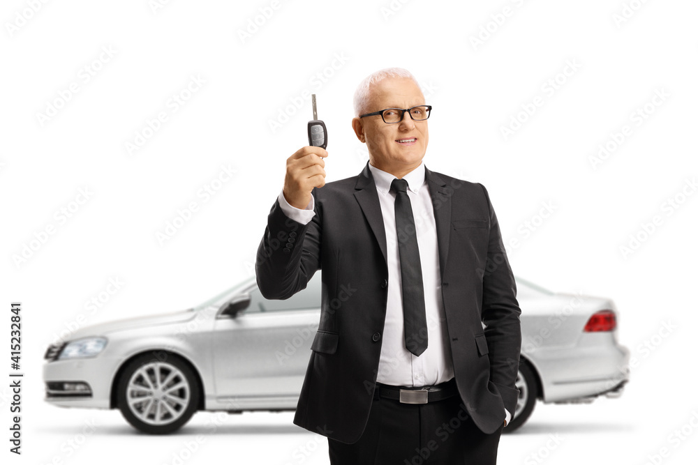 Naklejka premium Professional ature man in a suit and tie holding a car key from a new silver car