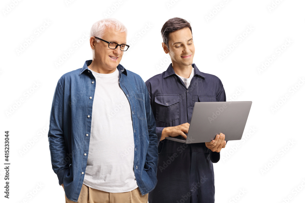 Mature man and a young auto mechanic worker looking at a laptop computer Mature man and a young auto mechanic worker looking at a laptop computer