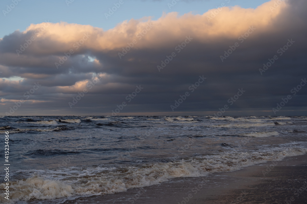 Wavy water of the Baltic sea and cloudy sky in the warm evening sunlight