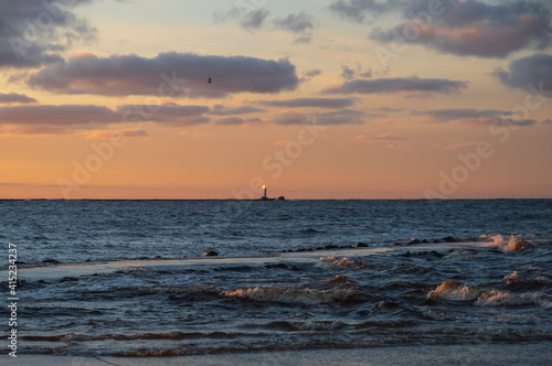 View to the Daugava river falling into the Baltic sea. Colorful sunset sky.  Daugavgriva lighthouse on the horizon. 