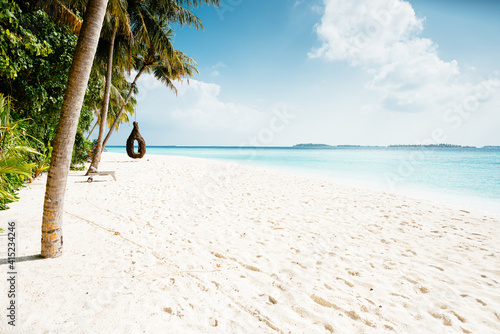 Azure coast of Maldives. Beach with palm trees  white sand  swing on the beach