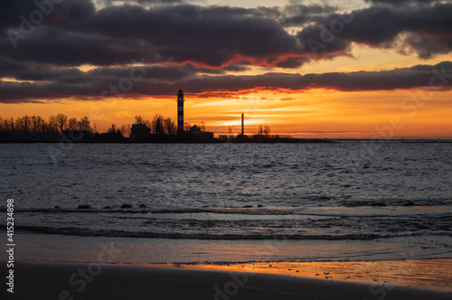 View to the Daugavgriva lighthouse from Mangalsala pier against colorful sunset sky