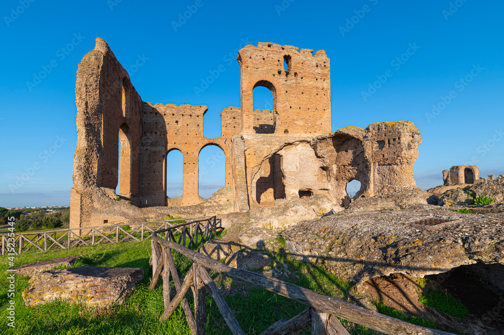 Ruins of the Imperial Villa dei Quintili, the thermal baths and the caldarium on the Via Appia in Rome, on a beautiful day of blue sky a suggestive panoramic image of the brick building.