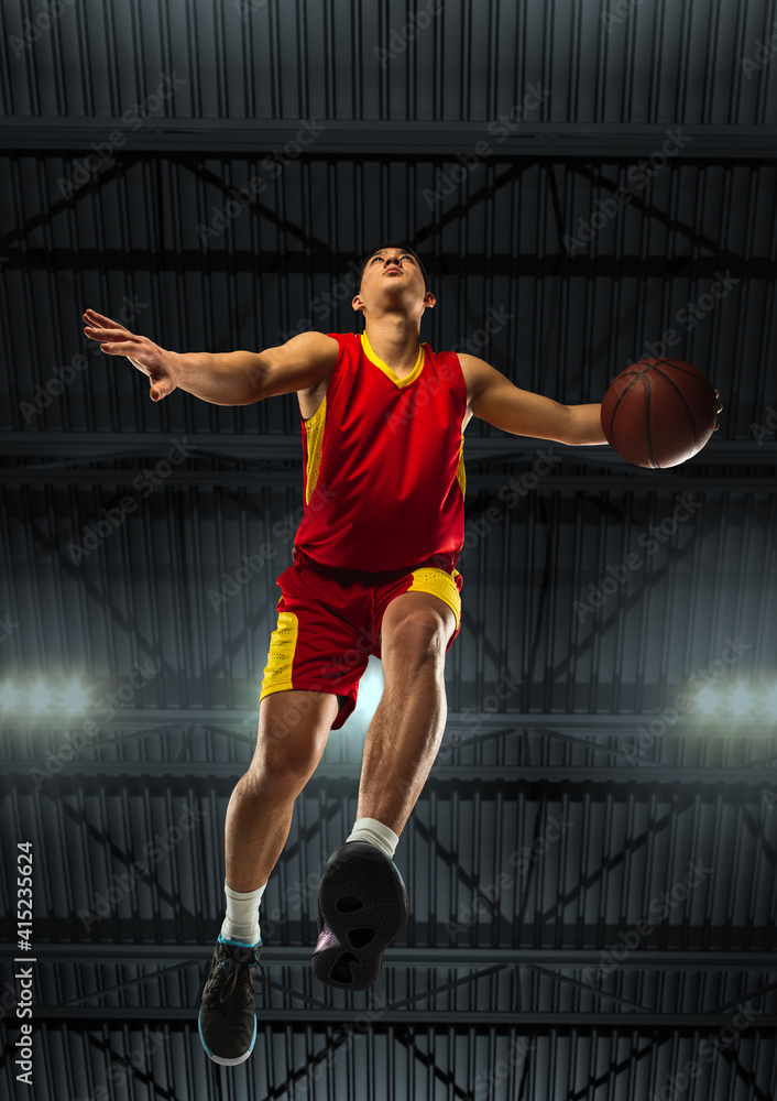 Young professional basketball player in action, motion isolated on black background, look from the bottom. Concept of sport, movement, energy and dynamic, healthy lifestyle. Training, practicing. Young professional basketball player in action, motion isolated on black background, look from the bottom. Concept of sport, movement, energy and dynamic, healthy lifestyle. Training, practicing.