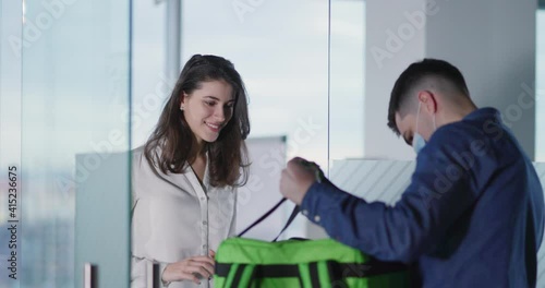 Food delivery. Young pretty caucasian woman receiving fast food order pakcage from young courier during quarantine. Fast services. photo