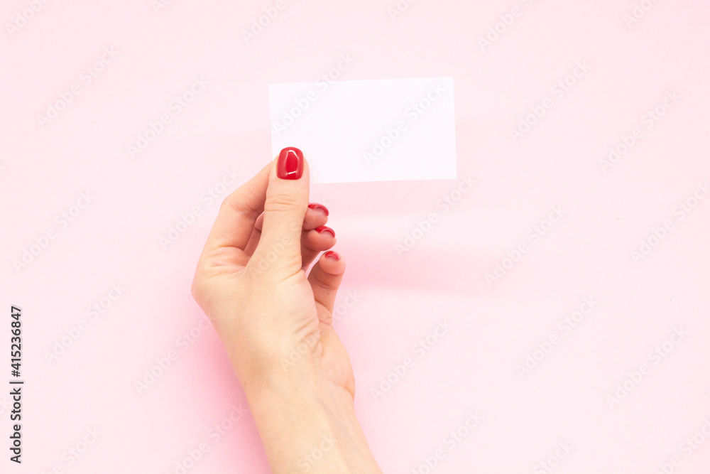 Woman's hand with fashionable red manicure holding business card on a pink background . Summer spring nail design. Woman's hand with fashionable red manicure holding business card on a pink background . Summer spring nail design.