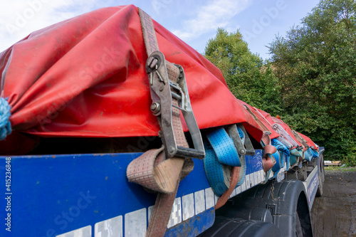 Semi Truck Trailer with a Load of Steel Sheeted with a Tarp and Held in Place with Ropes and Ratchet Straps