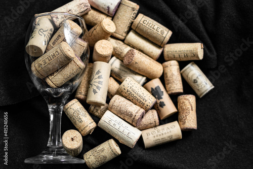 Bunch of wine corks and a glass over a black blanket
