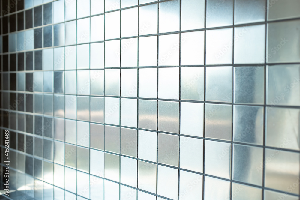 A closeup view of a background of metallic reflective silver tiles as a wall facade. A closeup view of a background of metallic reflective silver tiles as a wall facade.