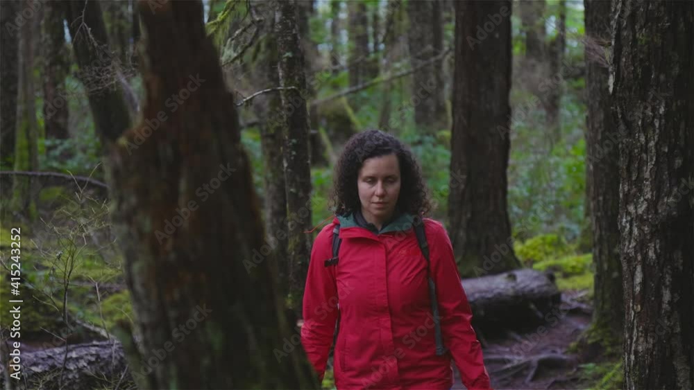 Girl Hiking on a Path in the Rain Forest during a rainy Winter Season. Squamish, North of Vancouver, British Columbia, Canada. Slow motion Girl Hiking on a Path in the Rain Forest during a rainy Winter Season. Squamish, North of Vancouver, British Columbia, Canada. Slow motion