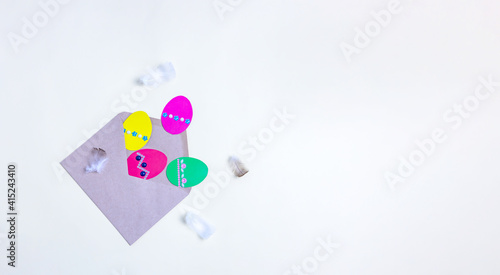 envelope with Easter eggs made of colored paper and feathers on a light background. DIY
