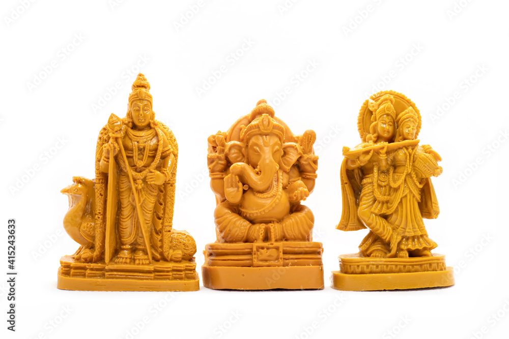 The hand-carved wooden idol of Lord Murugan with Radha Krishna and Ganesha is isolated on a white background The hand-carved wooden idol of Lord Murugan with Radha Krishna and Ganesha is isolated on a white background