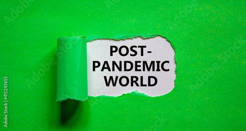 Post-pandemic world symbol. The words 'Post-pandemic world' appearing behind torn green paper. Beautiful green background, copy space. Medical and COVID-19 pandemic post-pandemic world concept.