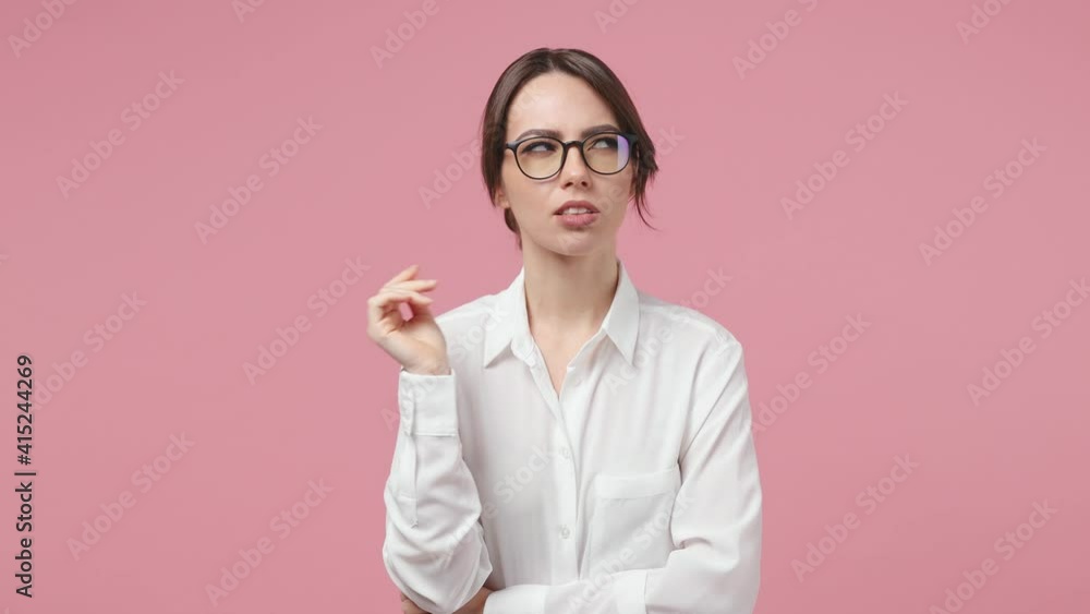 Puzzled pensive young business woman in white shirt glasses look aside up put hand prop up on chin iterates over solution options isolated on pink background studio. Achievement career wealth concept Puzzled pensive young business woman in white shirt glasses look aside up put hand prop up on chin iterates over solution options isolated on pink background studio. Achievement career wealth concept