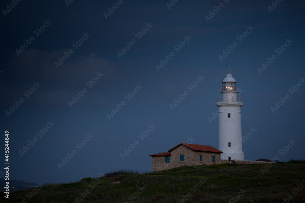 White beautiful lighthouse on the background of the night blue sky. Cyprus. Pathos.