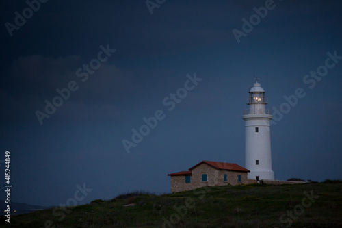 White beautiful lighthouse on the background of the night blue sky. Cyprus. Pathos.