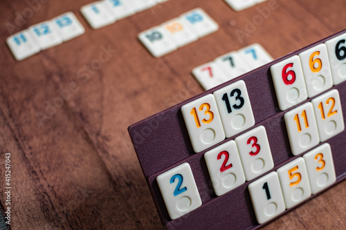 Rummi game tiles laying on a plastic rack simulating wood, in a mosaic style

