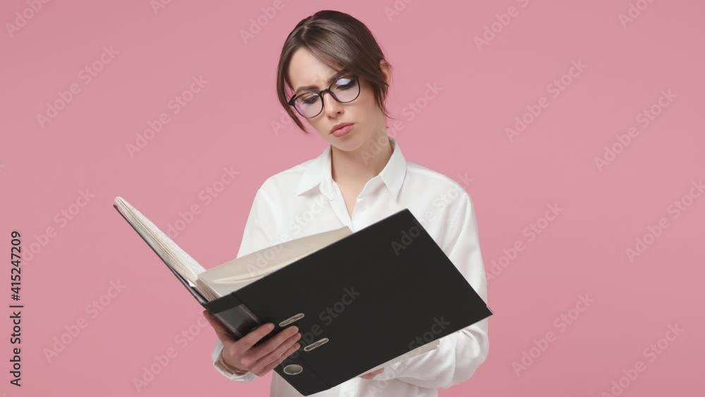 Smiling young brunette business woman 20s in white shirt glasses isolated on pink background studio. Achievement career wealth concept. Work with financial statistics papers documents in black folder Smiling young brunette business woman 20s in white shirt glasses isolated on pink background studio. Achievement career wealth concept. Work with financial statistics papers documents in black folder